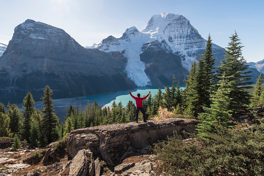 Man with arms raised, on a ridge above Berg lake and mountains, Mount Robson, Canada