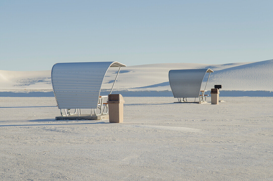 Shelters and trash bins among gleaming white sand dunes, White Sands National Monument, USA