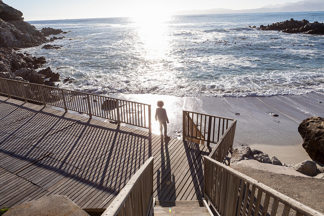 A boy running towards the beach down a set of steps