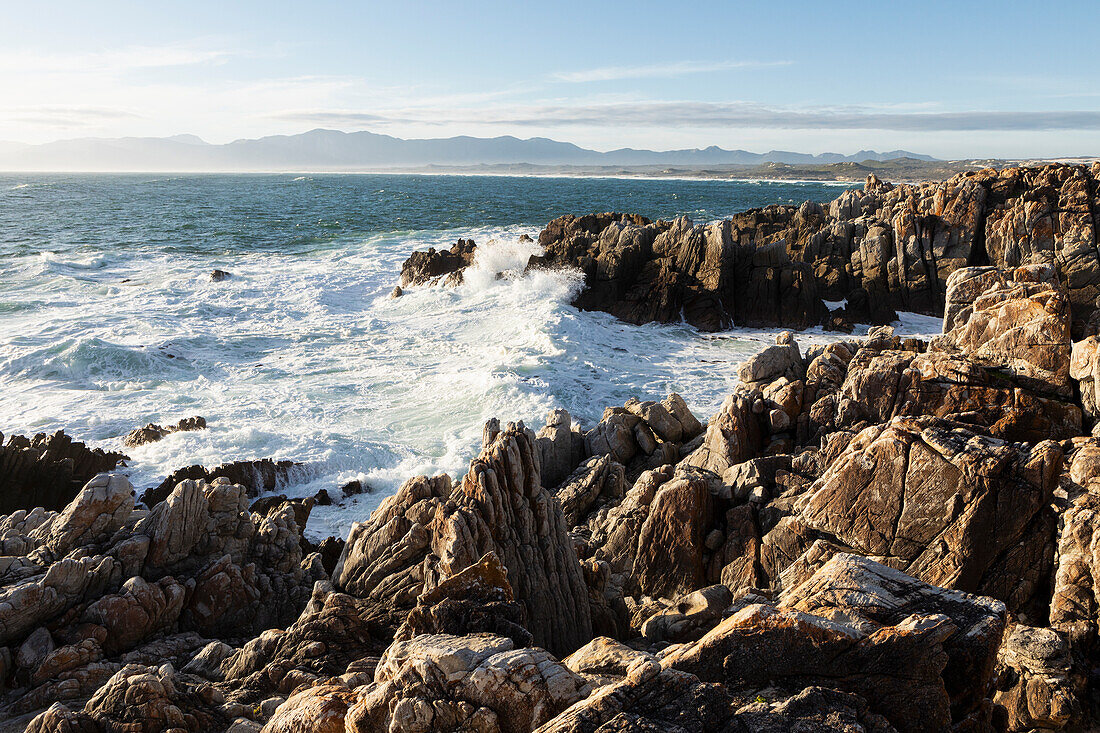 Die zerklüfteten Felsen und Felsenbecken an einer Meeresküste mit brechenden Wellen