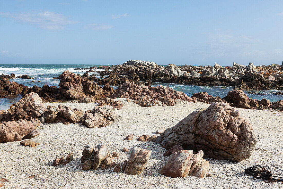 Sand- und Kiesstrand mit schroffen Felsen an der Atlantikküste.