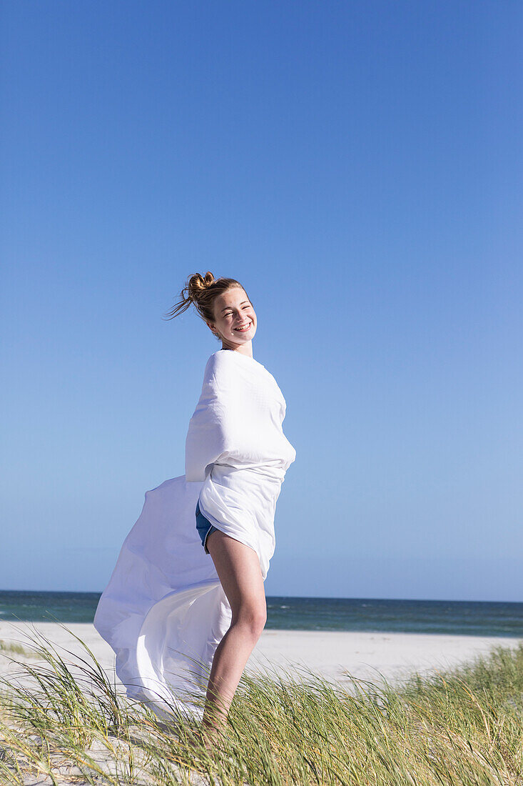 Teenage girl wrapped in white, Grotto Beach, Hermanus, Western Cape, South Africa.