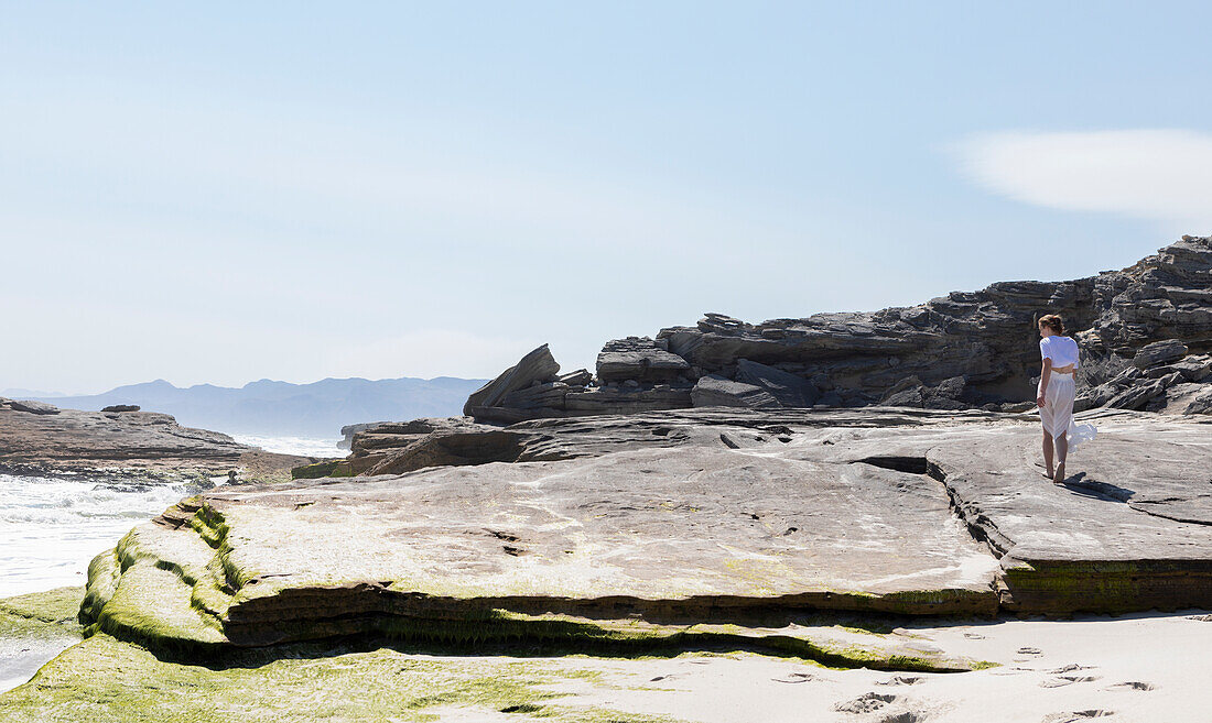 Teenage girl exploring a rocky shore on the Atlantic ocean coastline, South Africa