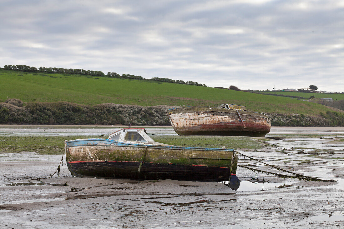 Two boats beached at low tide,with muddy hulls and frayed mooring lines