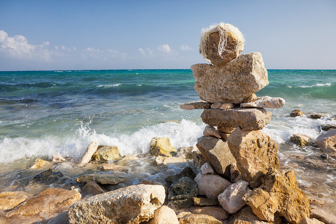 A cairn, pile of stones on the beach at the water's edge