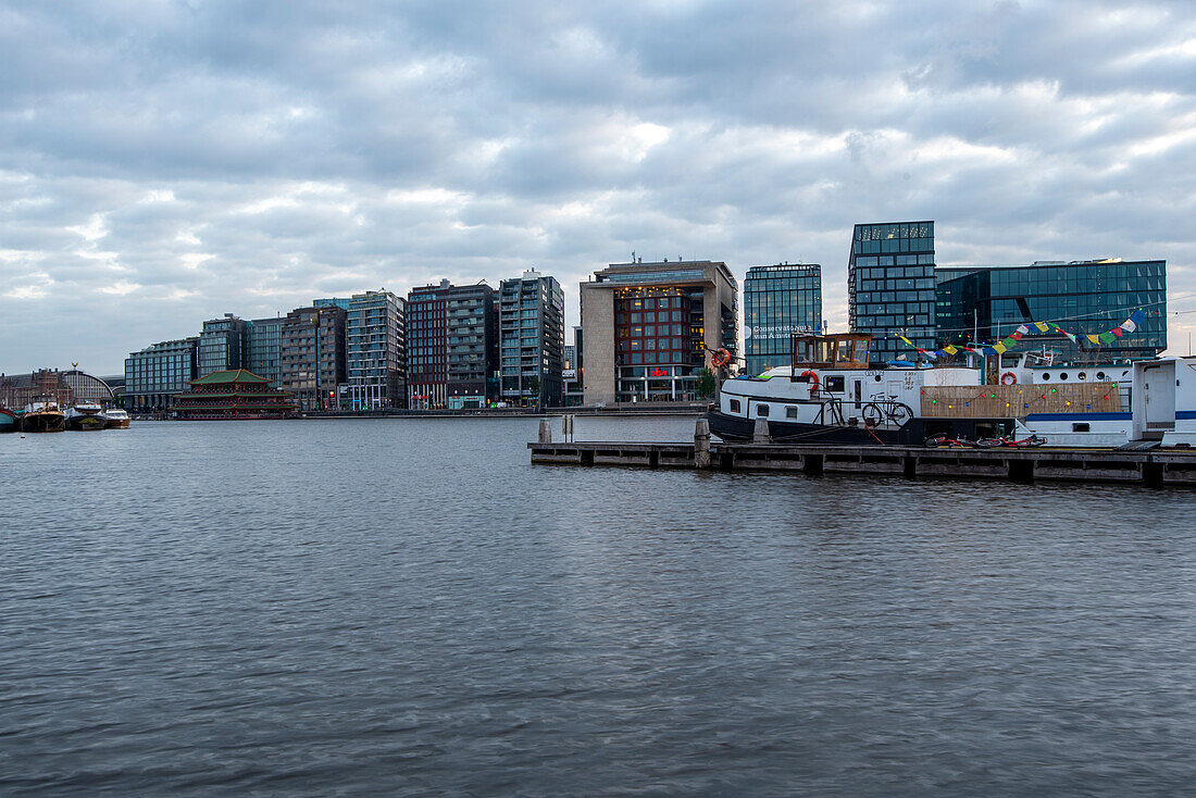 Houseboat, modern apartment buildings at Amsterdam Centraal Central Station, dawn, Amsterdam, North Holland, Netherlands