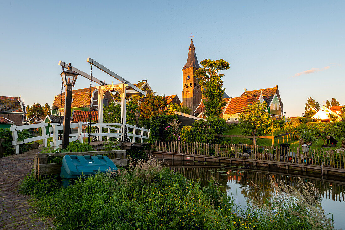 Evening sun, wooden bridge, canal with water lilies, houses, village church, Marken peninsula, Waterland, North Holland, Netherlands