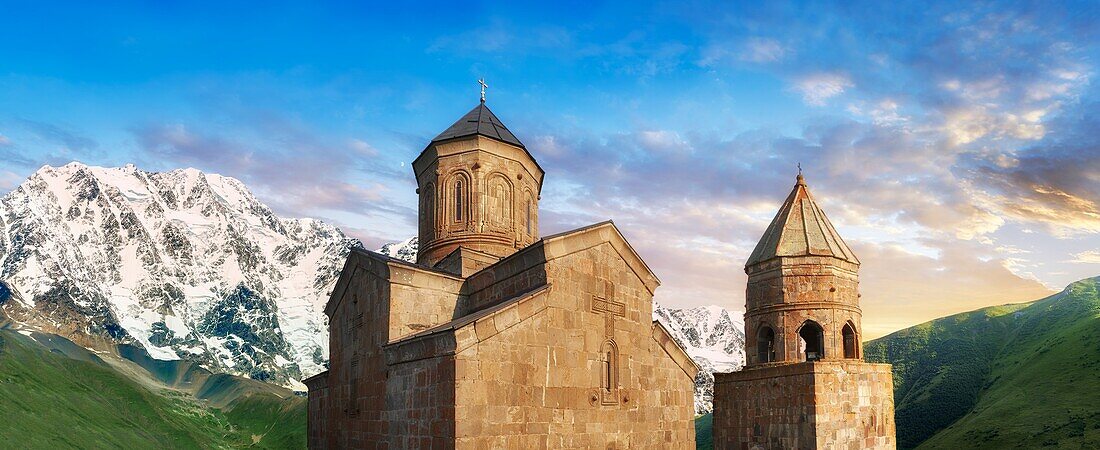 Gergeti Holy Trinity (Tsminda Sameba) Georgian Orthodox and Apostolic Church and bell tower,14th century,Gergeti,Khevi province,Georgia (country). At Sunset.