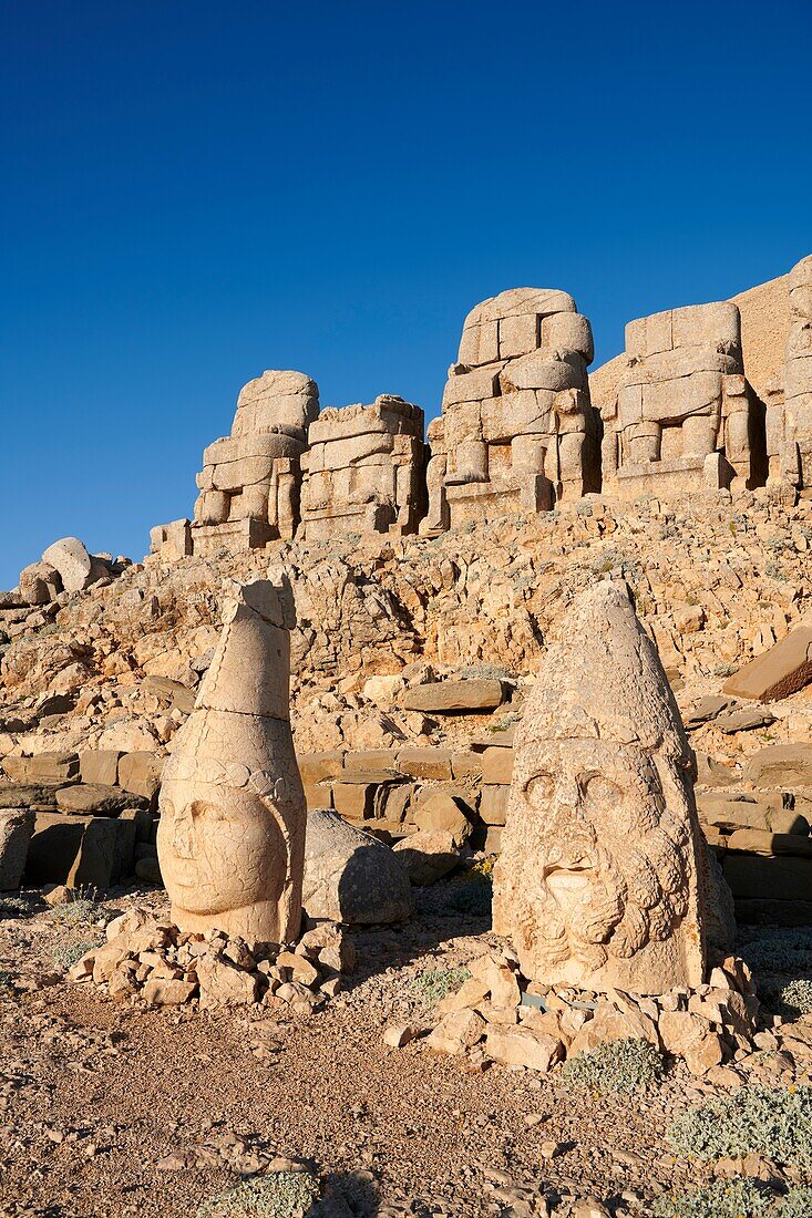 Statue heads,from right,Herekles & Apollo with headless seated statues in front of the stone pyramid 62 BC Royal Tomb of King Antiochus I Theos of Commagene,east Terrace,Mount Nemrut or Nemrud Dagi summit,near AdA±yaman,Turkey.