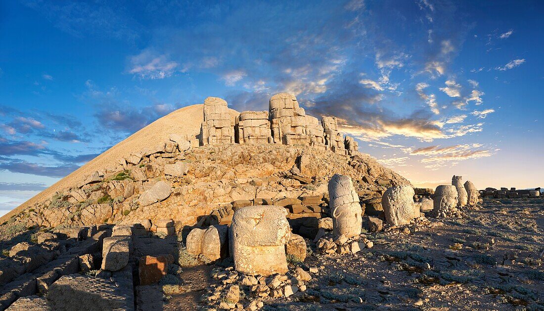 Statue heads at sunset,from left,Eagle,Antiochus,Commagene,Zeus,Apollo,& Herekles with headless seated statues in front of the stone pyramid 62 BC Royal Tomb of King Antiochus I Theos of Commagene,east Terrace,Mount Nemrut or Nemrud Dagi summit,near AdA±yaman,Turkey.