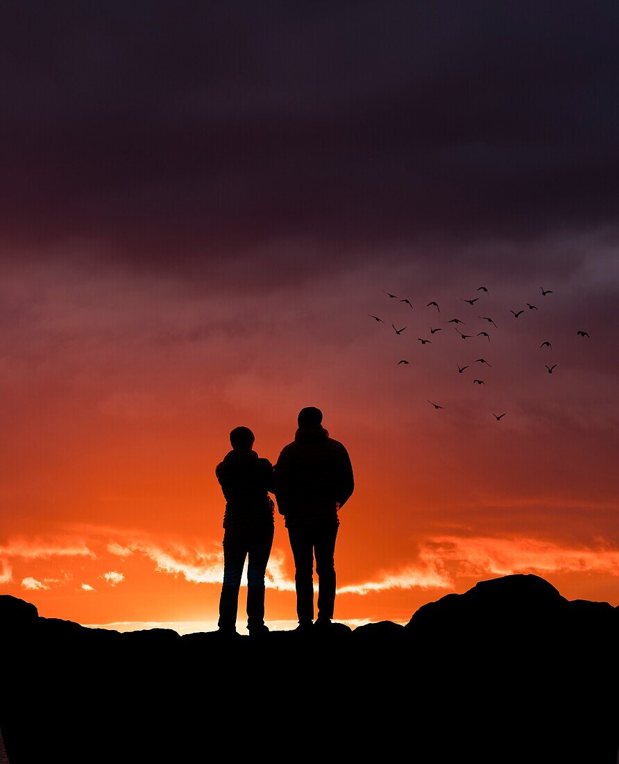 Paar beobachtet den Sonnenuntergang in der Grotta, Reykjavik, Island.