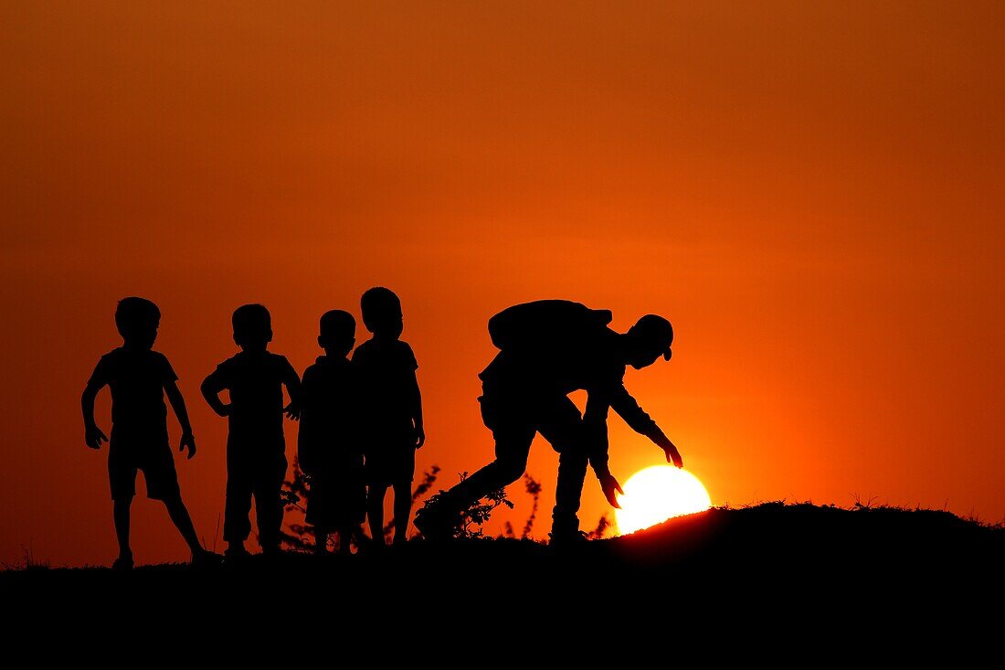 Silhouette des Mannes mit den Kindern, die Sun, Maharashtra, Indien berühren.