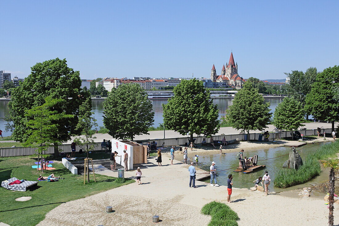 Wasserspielplatz auf der Donauinsel, im Hintergrund die Franz-von-Assisi-Kirche des 2. Bezirks, Wien, Österreich