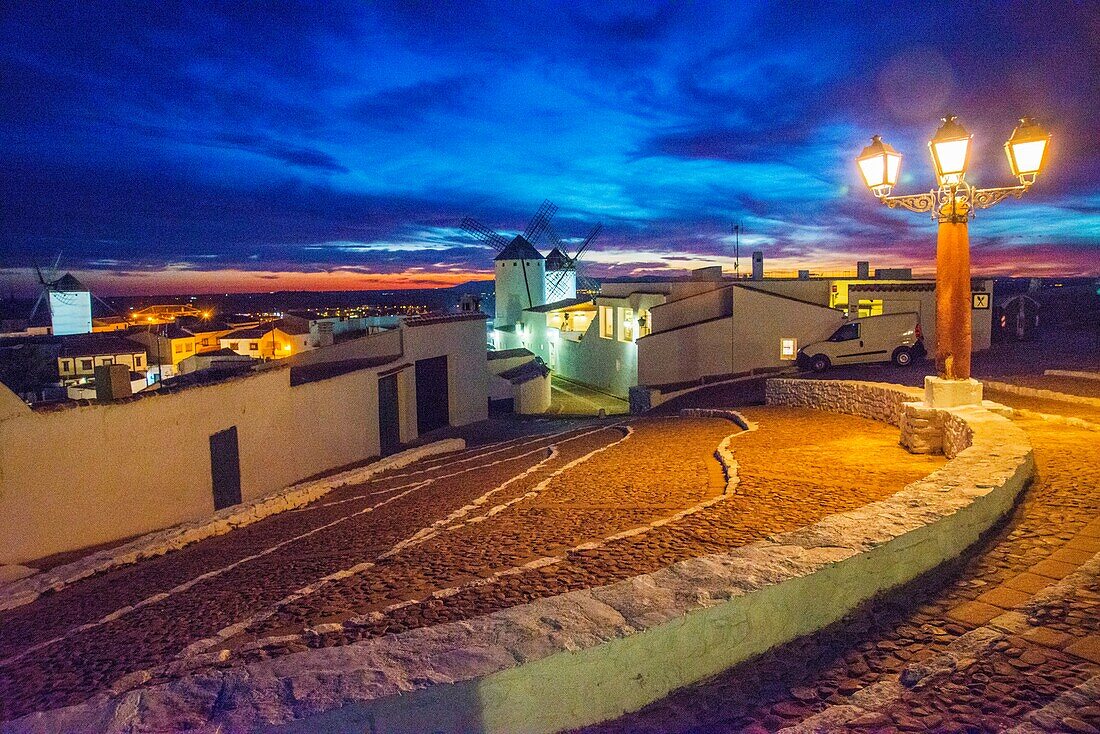 Straße und Windmühlen, Nachtansicht. Campo de Criptana, Provinz Ciudad Real, Castilla La Mancha, Spanien.
