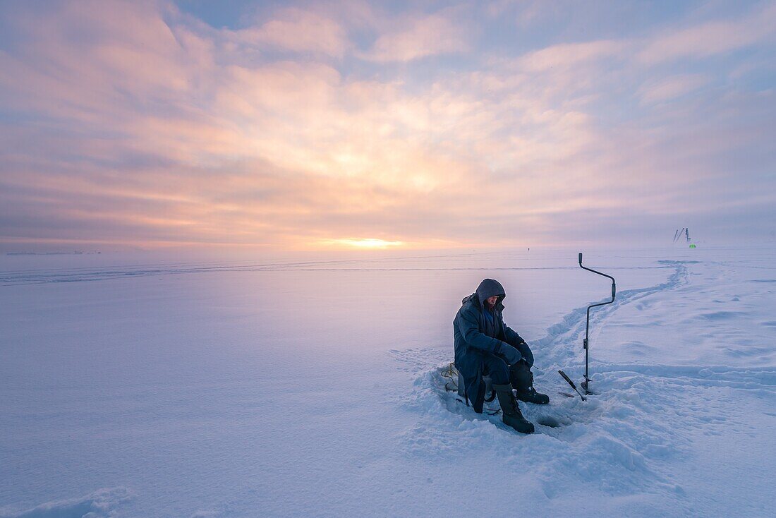 Fischer in der gefrorenen Ostsee mit Schnee im Winter und Sonnenuntergang in St. Petersburg, Russland.