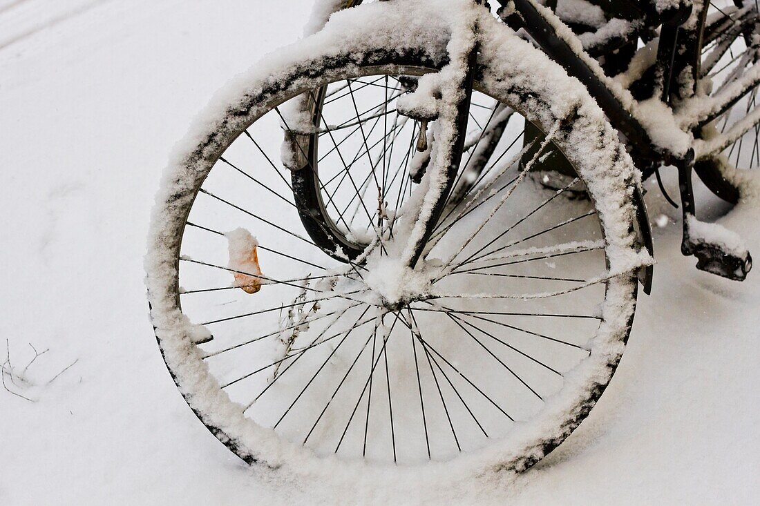 Ein schneebedecktes Fahrradrad nach einem starken Schneefall im Winter in Berlin, Deutschland.