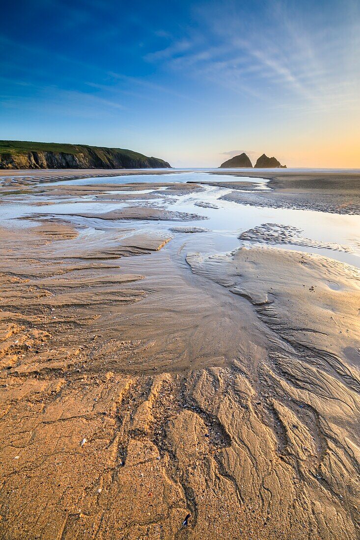 Sandmuster am Strand von Holywell Bay an der Nordküste von Cornwall, aufgenommen kurz vor Sonnenuntergang an einem Abend im Mai. Eine lange Verschlusszeit wurde verwendet, um die Wellen auf der Oberfläche der Wasserbecken abzuflachen.