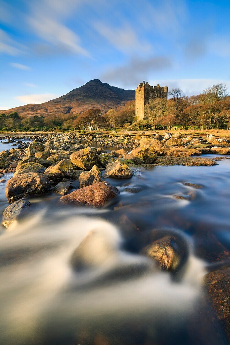 Moy Castle at the head of Loch Buie on the Isle of Mull illuminated by late afternoon sunlight. A long shutter speed was utilised to blur the movement in the foreground stream and the clouds.