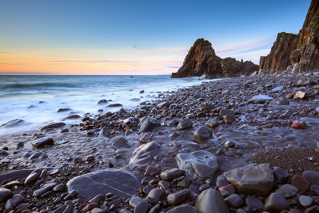 Ein Bach am Mouthmill Beach in North Devon, aufgenommen bei Sonnenuntergang Anfang Juli mit Blackchurch Rock in der Ferne.