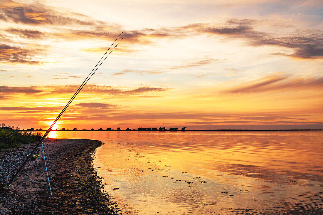 Angelruten im Sonnenuntergang mit Blick auf den Graswarder, Heiligenhafen, Sonnenuntergang, Strandhusen, Ostsee, Ostholstein, Schleswig-Holstein, Deutschland\n