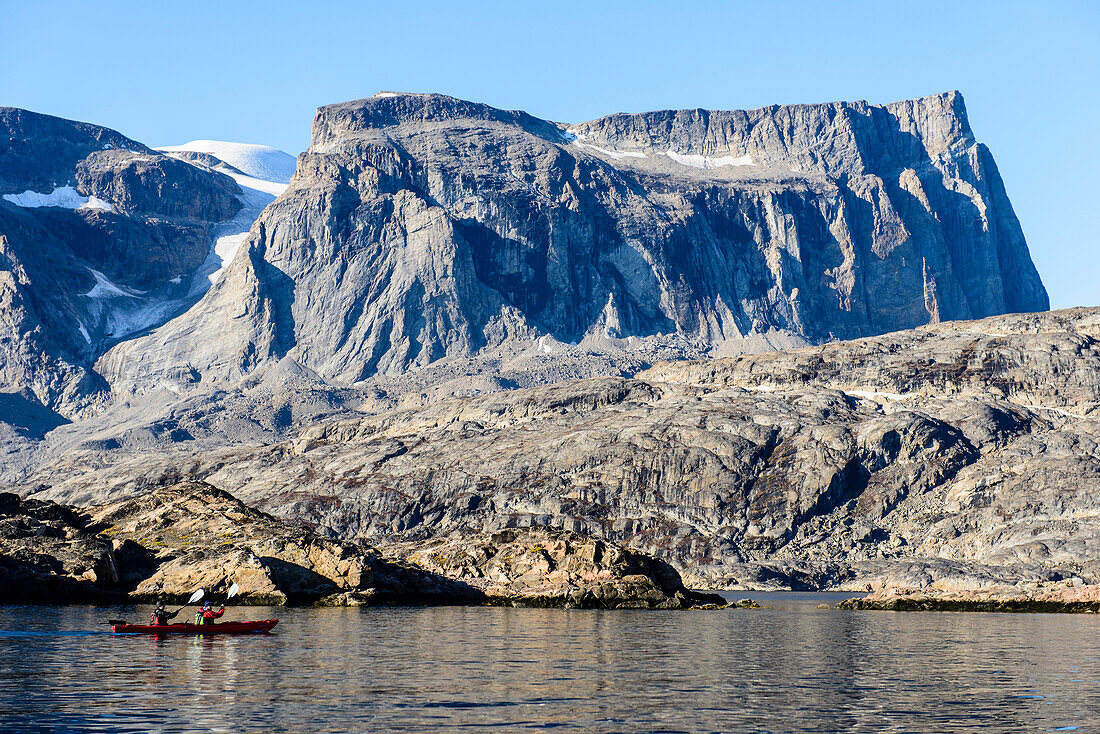Zwei Kajakfahrer auf dem Wasser vor der felsigen Küste, Grönland