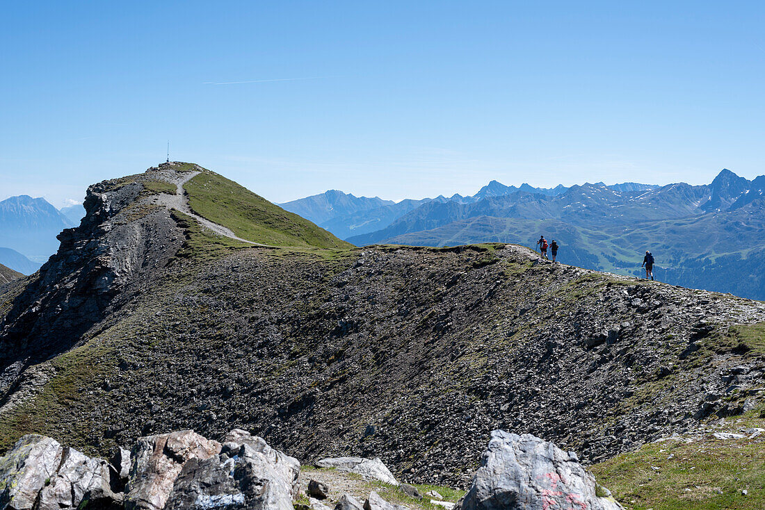 Hikers on the E5 European long-distance hiking trail, crossing the Alps, Piller summit cross, Wenns, Tyrol, Austria
