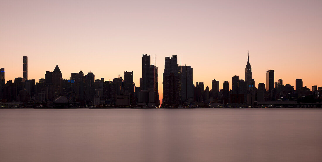 USA, NY, New York City, Midtown Manhattan seen across river at sunset