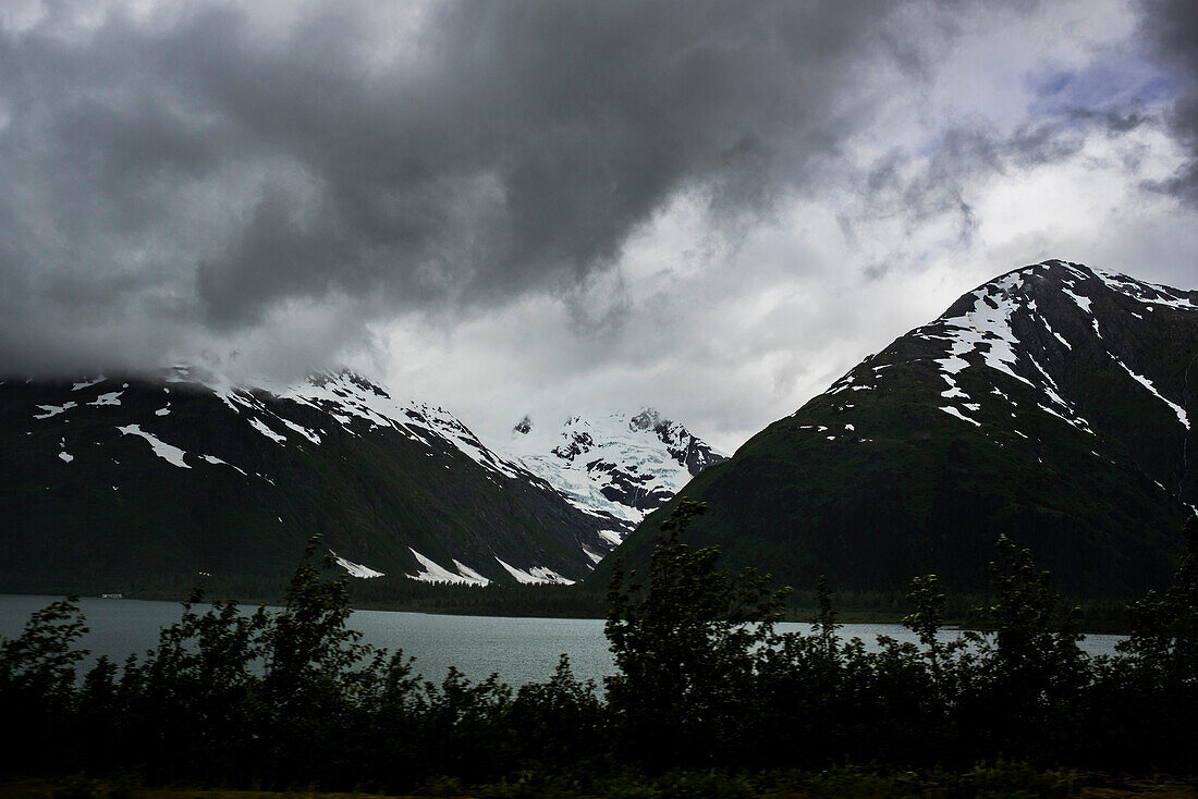 USA, Alaska, Storm clouds above lake and mountains