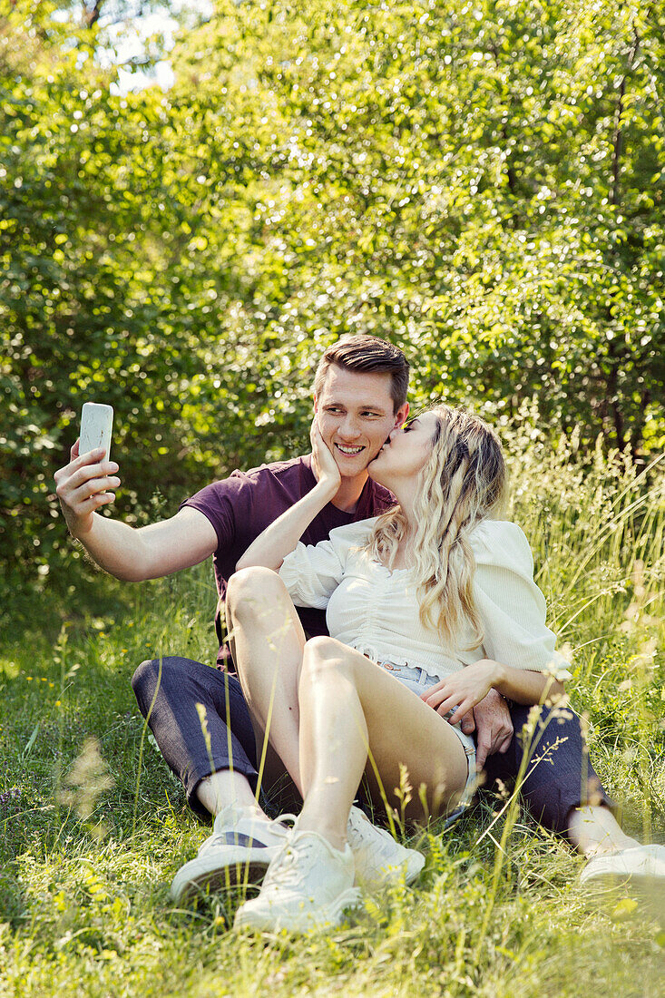 Austria, Vienna, Smiling young taking selfie in park