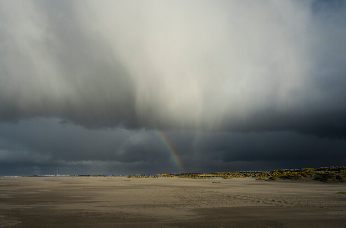 Rain clouds and rainbow over sand dunes
