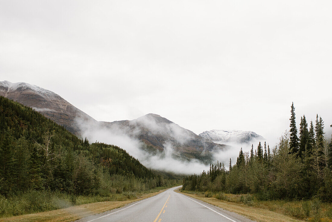 Canada, Yukon, Whitehorse, Empty road crossing hilly landscape in fog