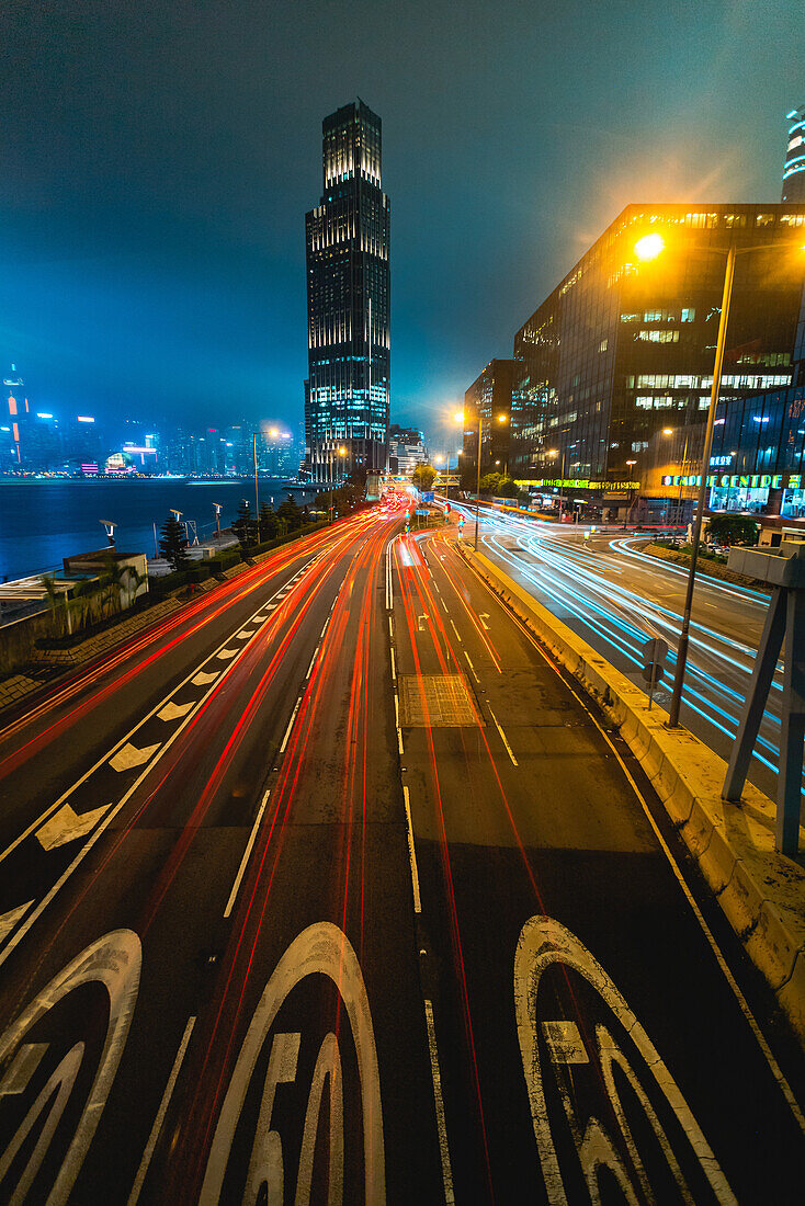 Langzeitbelichtung des Verkehrs auf der Stadtstraße mit modernen Gebäuden im Hintergrund, Hongkong