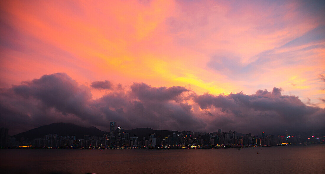 Blick auf die Skyline der Stadt unter den Gewitterwolken bei Sonnenuntergang, Hongkong, China