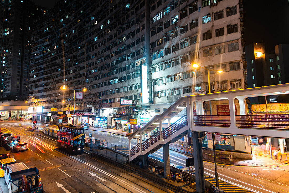 Ansicht des Gebäudes und der Geschäfte mit dem Fahrzeug, das sich auf der Straße bewegt, Hongkong