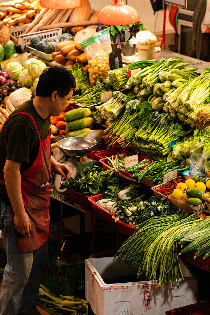 Mann verkauft Gemüse auf dem Markt, Macao