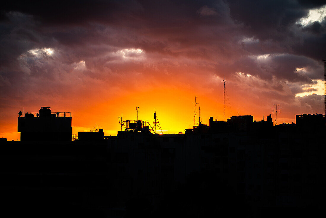 Silhouetted buildings against cloudy sky at sunset