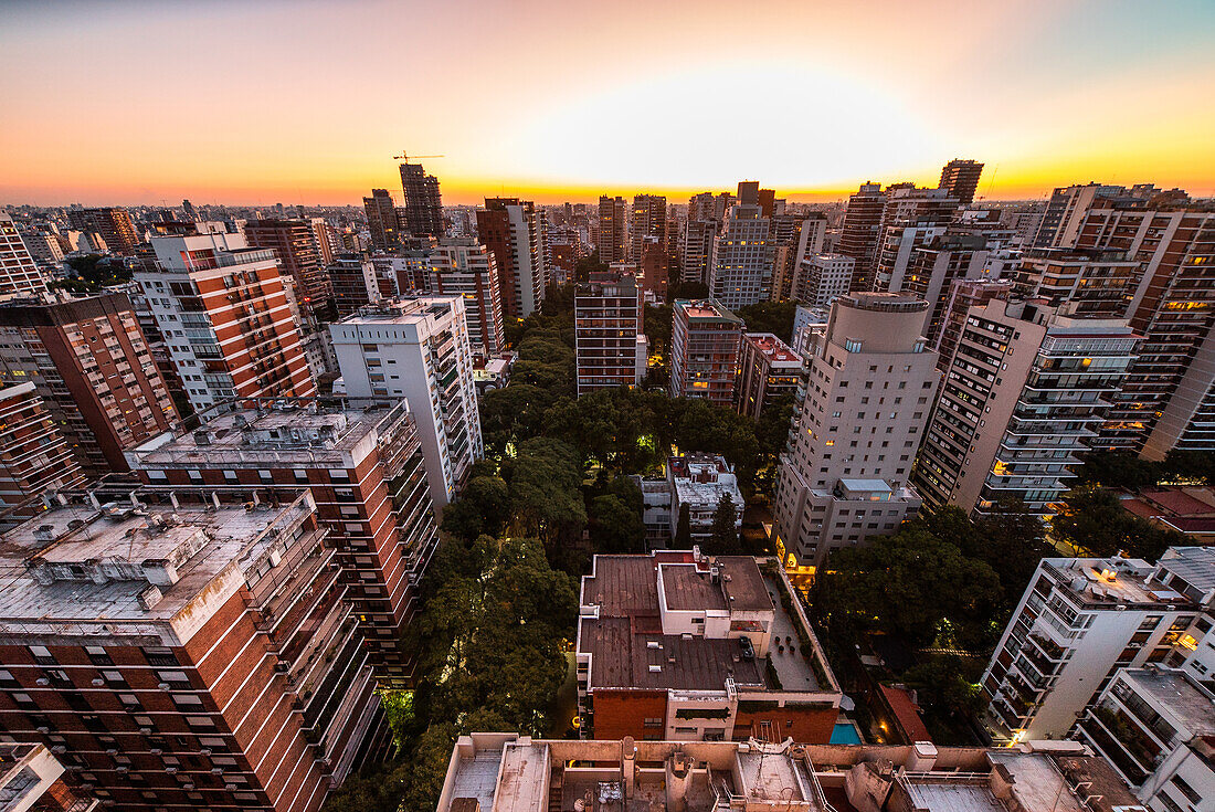 Aerial view of crowded cityscape with high rise buildings at sunset