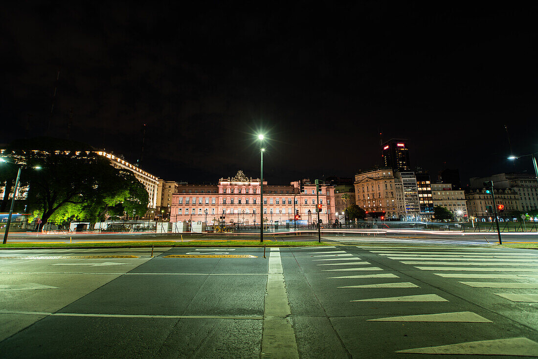 View of traffic driving on street with government building Casa Rosada in background