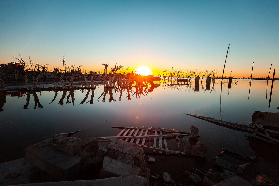 Blick auf kahle Bäume und verlassenes Dorf an der Küste bei Sonnenuntergang, Villa Epecuen