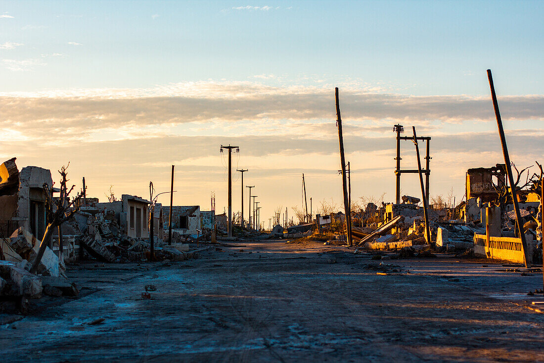 Ansicht der unbefestigten Straße, die durch verlassenes Dorf gegen bewölkten Himmel, Villa Epecuen führt