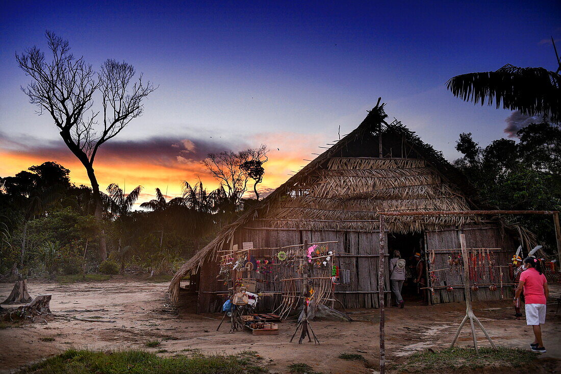 Die Sonne geht über strohgedeckten Hütten im Dorf Tijuca unter, nahe Manaus, Amazonas, Brasilien, Südamerika (Montage)