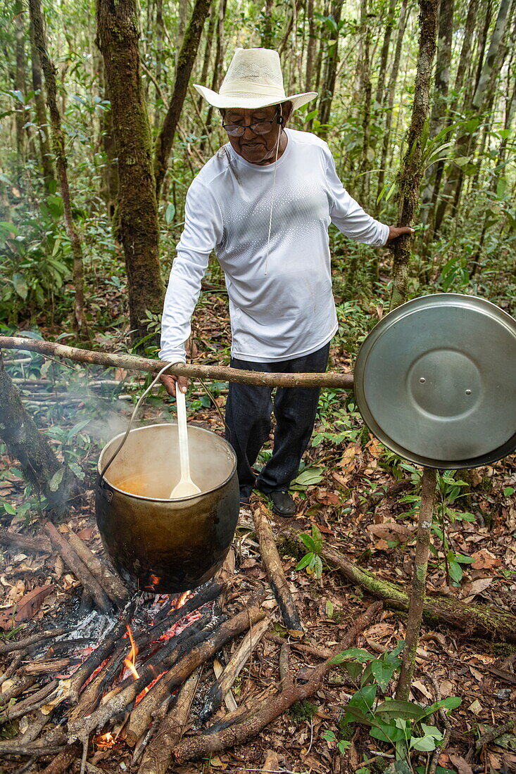 A Brazilian naturalist guide heats soup over an open fire, near Manaus, Amazon, Brazil, South America