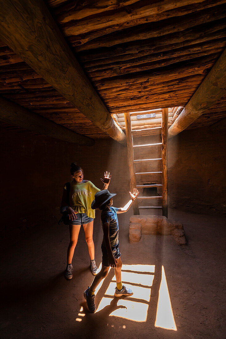 Boy (8-9) and girl (14-15) exploring Native American kiva in Pecos National Monument
