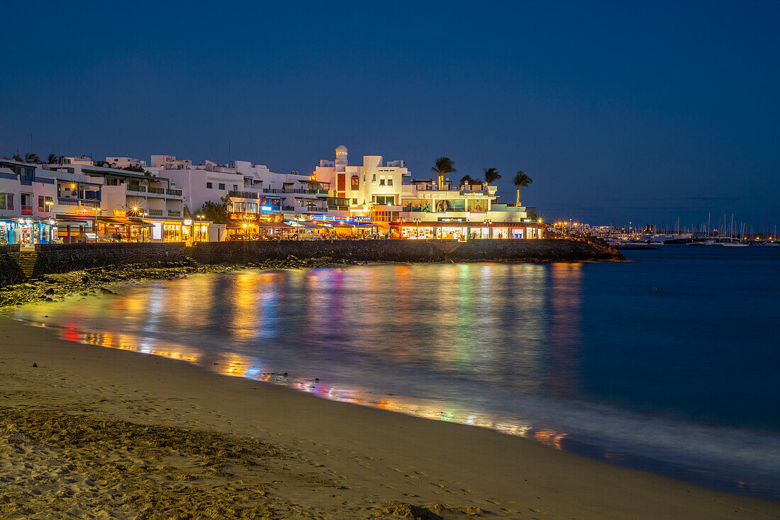 Blick auf Restaurants und Geschäfte mit Blick auf den Strand von Playa Blanca in der Abenddämmerung, Playa Blanca, Lanzarote, Kanarische Inseln, Spanien, Atlantik, Europa
