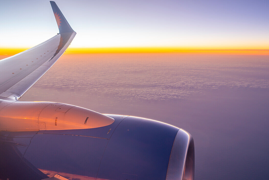 Blick auf Flugzeugmotor und Wolken über dem Meer bei Sonnenuntergang, Atlantik, Europa