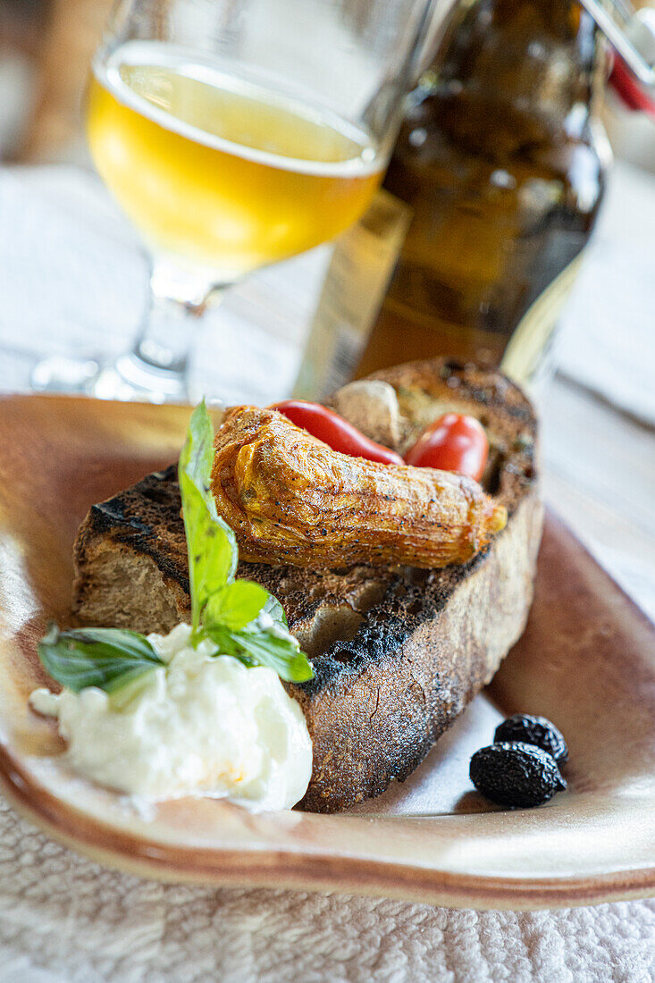 Griechische Vorspeise mit gefüllten Zucchiniblüten, serviert mit Bruschetta und Tzatziki-Sauce in Holzschale, Kreta, griechische Inseln, Griechenland, Europa