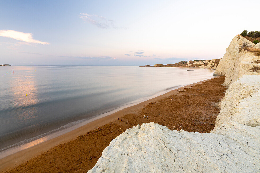 Ruhiges Meer im Morgengrauen, eingerahmt von Kalksteinfelsen mit Blick auf den goldenen Sand von Xi Beach, Kefalonia, Ionische Inseln, Griechische Inseln, Griechenland, Europa