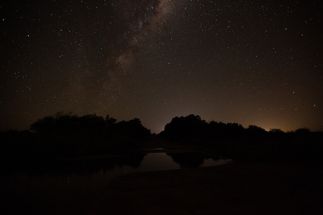 Scenic view of milky way over rural landscape with standing water