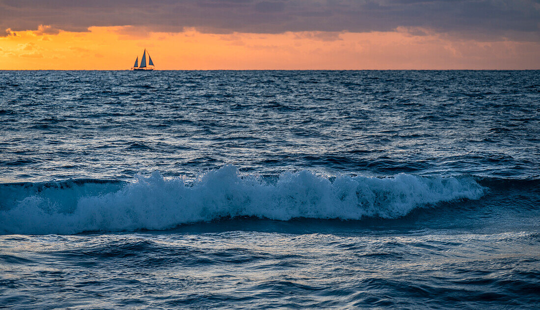 USA, Florida, Boca Raton, Sonnenaufgang über dem Meer mit Silhouette des Segelboots in der Ferne