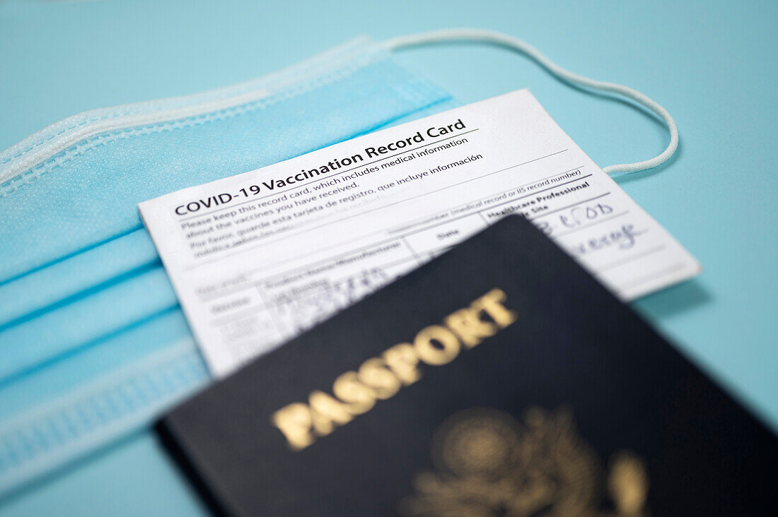 Covid-19 vaccination record card with passport and blue face mask